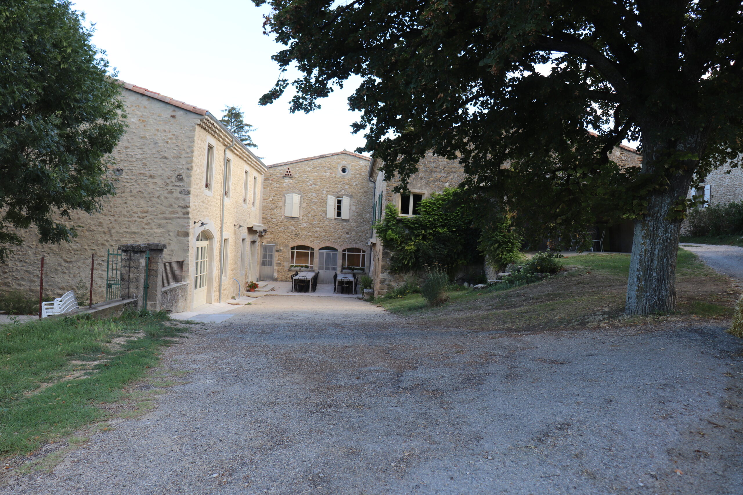 Le domaine de La Croisée à Ourches : bâtisses de pierre, grands arbres et cour ensoleillée