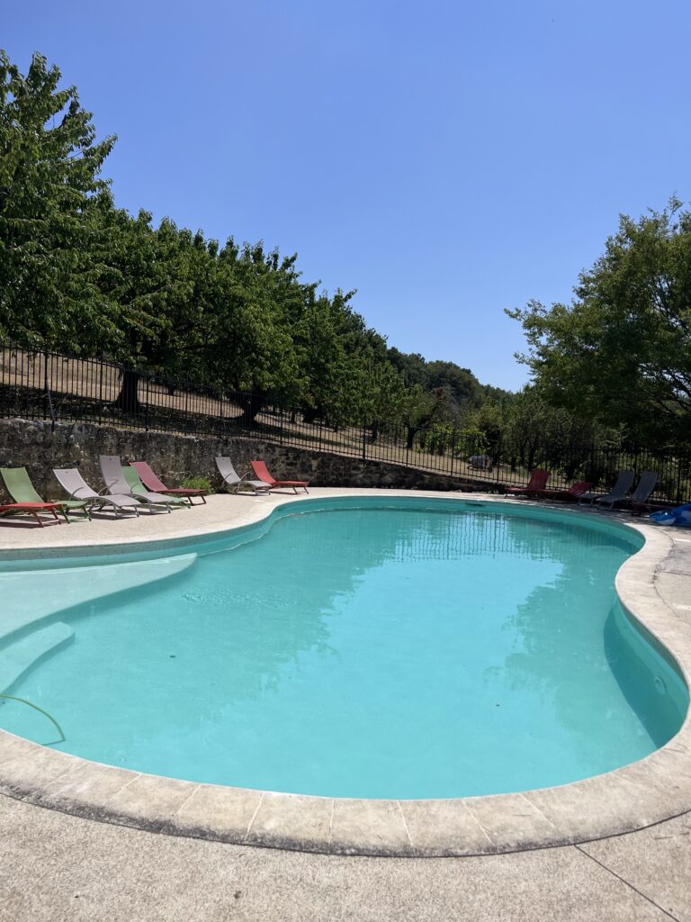 La piscine de La Croisée, bordée de transats et d’arbres